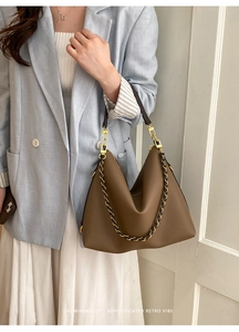 Detailed macro of brown leather tote showing litchi grain texture and gold chain detail