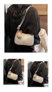 Detail showing metallic silver shoulder bag with a cute teddy bear charm and knotted strap