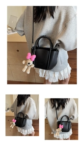 Black lychee texture bucket bag detail with cute plush puppy charm and shoulder strap