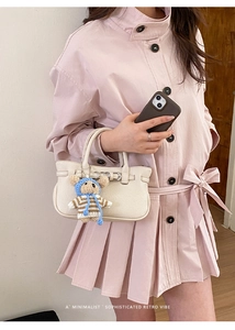 Detailansicht der cremefarbenen Mini-Lederhandtasche mit Litschistruktur und Bärenanhänger