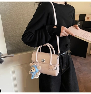 Close-up of pink PU leather handbag with metal lock and cute blue bear plush charm