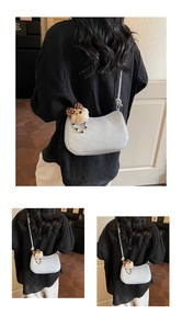 Detail of light grey crossbody bag with a plush bear charm and vintage beaded chain strap