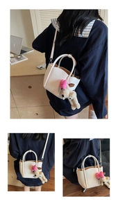 Detail of white litchi pattern leather bucket bag with cute plush puppy charm