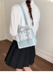 Detail view of a blue and white preppy satchel with bear print and golden buckle straps