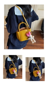 Detail of yellow lychee leather bucket bag with cute white puppy plush charm and strap