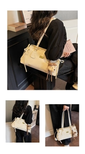 Detail view of cream shoulder bag with bow accents and a plush bear pendant charm