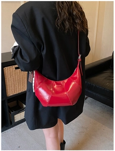 Model view of a red crescent leather crossbody bag with vertical stitching details