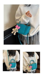 Detail view of sky blue leather handbag with a cute puppy plush charm and soft shoulder strap