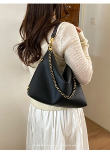 Detailed view of black pebbled leather tote with golden chain and retro dumpling shape