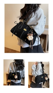 Close-up of black tote bag with white contrast stitching and a plush dog charm detail