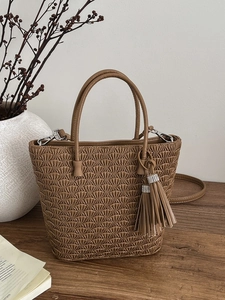 Sac seau plissé marron avec pompon et strass sur une surface en bois