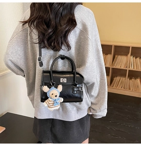 Detail of vintage black leather handbag featuring a silver twist lock and cute bear charm