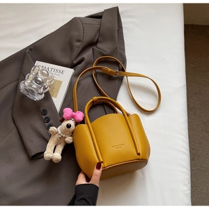 Detail of mustard yellow lychee grain leather bucket bag with cute puppy plush charm