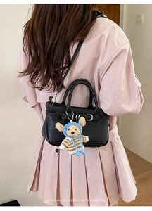 Detailansicht der schwarzen Handtasche aus Narbenleder mit süßem Teddybär-Anhänger