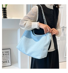 Close-up of light blue denim hobo bag featuring a stylish silver chain woven strap