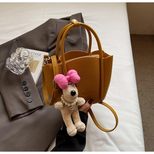 Detail of ginger yellow pebbled leather handbag with cute puppy charm and adjustable strap