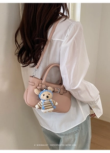 Rosa Schultertasche aus genarbtem Leder mit süßem Bärenanhänger an der Seite am Modell