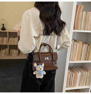 Detail of vintage brown shoulder bag with silver clasp and a cute bear charm pendant