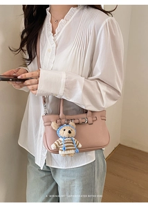 Rosa Handtasche aus Leder mit Litschimuster und Bärenanhänger an einem Lifestyle-Modell