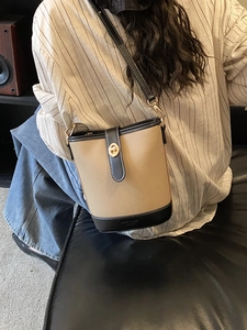 Elegante borsa a secchiello bicolore in pelle beige e nera con chiusura a scatto dorata