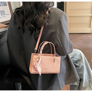 Detailed view of pink croc-embossed handbag with silk scarf handle and detachable strap