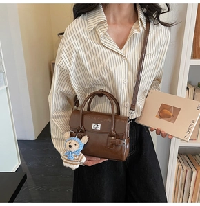 Detailed shot of brown vintage handbag featuring metal twist lock and cute bear charm