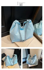 Detail of light blue denim tote with drawstring closure and silver chain shoulder strap