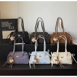 Detail view of multi-color suede shoulder bags with gold logos and teddy bear charms