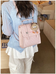 Detailed back view of a pink polka dot mini backpack worn by a model in a casual outfit