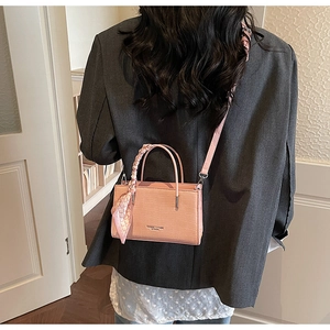 Pink stone texture handbag worn by model showing side profile and elegant silk scarf detail