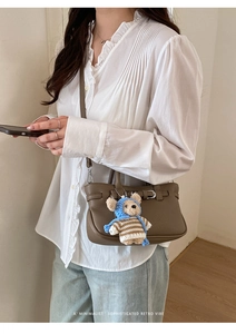 Detail der Retro braunen Lederhandtasche mit Teddybär Anhänger und goldenen Metallschnallen