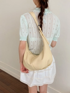 Cremefarbene Hobo-Tasche in Halbmondform mit verstellbarem Riemen am Model präsentiert