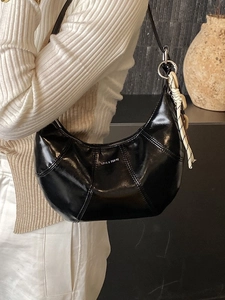 Glossy black crescent shoulder bag with LOVE & DESIRE print and woven charm on a model