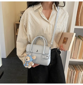 Detail of light blue faux leather handbag with silver twist lock and bear charm accessory