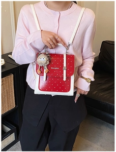 Red polka dot mini backpack with monster charm shown worn by a model in casual setting