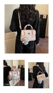 Detail view of pink glossy leather crossbody bag with teddy bear charm and adjustable strap