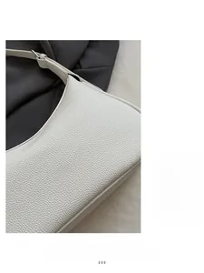 Detail of white lychee pattern leather and silver hardware on a minimalist underarm bag
