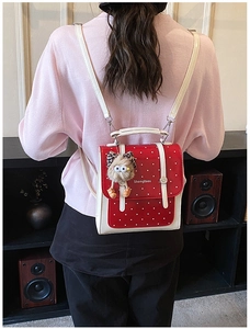 Detailed view of red polka dot mini backpack with cute plush charm on female model