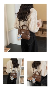 Detail view of brown vintage PU leather handbag with metal twist lock and cute bear charm