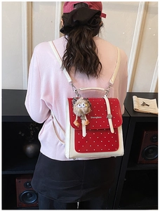 Detail of red polka dot mini backpack with flip cover and brown plush pendant