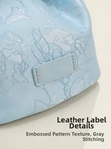 Détail du sac seau en jacquard bleu clair avec texture gaufrée et étiquette en cuir