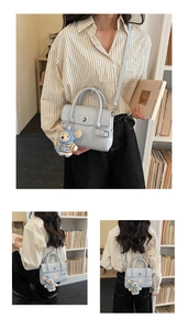 Detail of blue leather handbag featuring silver twist lock and cute bear plush charm