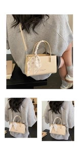 Detail of beige crocodile pattern handbag with elegant floral scarf on handle