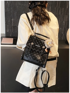 Close-up of black polka dot mini backpack with plush pendant and magnetic buckle