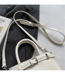Detail of white leather handbag featuring adjustable strap and elegant buckle design