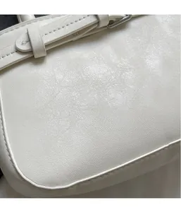 Detail of white leather bag featuring fine lychee grain texture and silver metal buckle