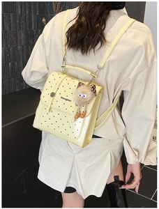 Detail of a creamy yellow mini backpack with black polka dots and a cute plush keychain
