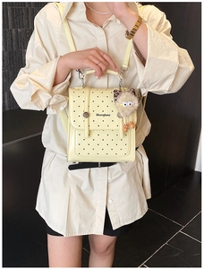 Polka dot yellow patent leather mini backpack with plush pompom and top handle detail