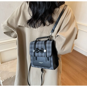 Detail of retro plaid small backpack with black leather trim and bow on model