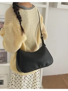 Close-up of black lychee-textured leather crescent bag with silver buckle worn by model